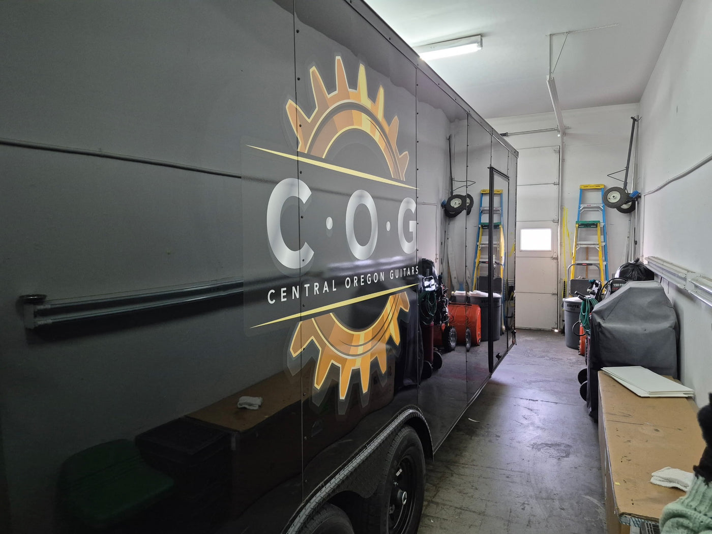 Trailer with 'COG Central Oregon Guitars' logo in a garage setting